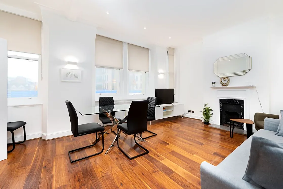 Apartment 1: Living and dining room with walnut floors, a fireplace and tall windows