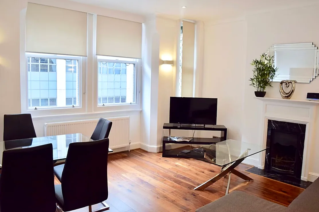 Apartment 2: Living room with tall sash windows, fireplace and dining table