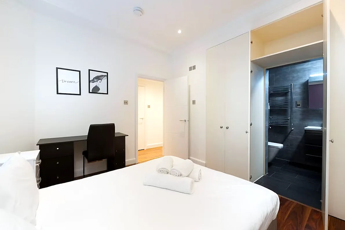 Bedroom with wardrobe and bathroom beyond